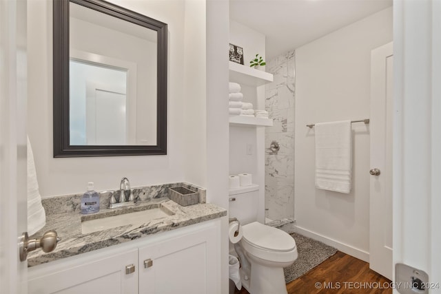 bathroom featuring a shower, wood-type flooring, vanity, and toilet