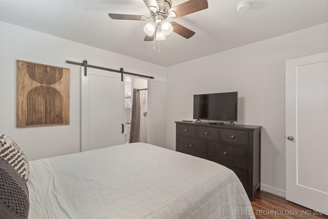 bedroom with a barn door, ceiling fan, and dark wood-type flooring