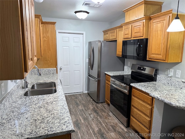 kitchen featuring sink, light stone counters, dark hardwood / wood-style flooring, decorative light fixtures, and appliances with stainless steel finishes