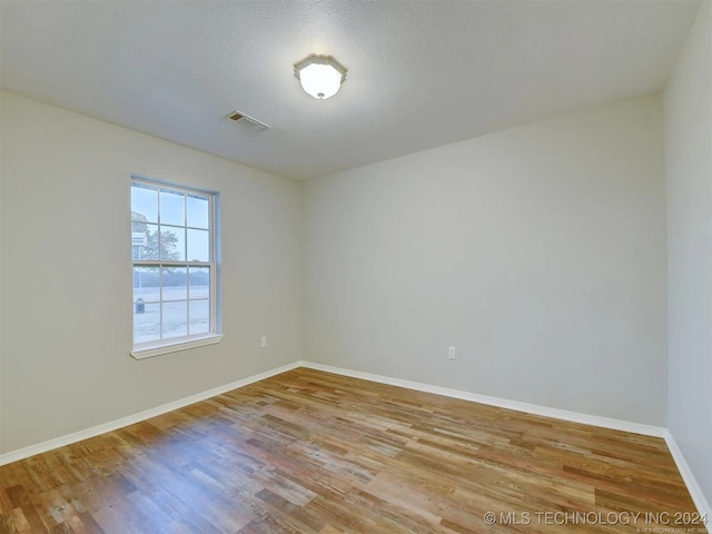 empty room with a textured ceiling and light hardwood / wood-style flooring