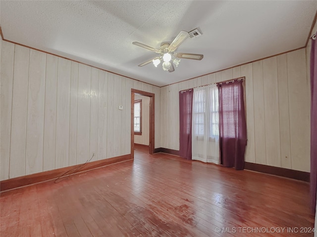 empty room featuring a healthy amount of sunlight, ceiling fan, and wood-type flooring