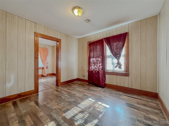 unfurnished room with hardwood / wood-style flooring and wooden walls