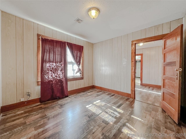 spare room featuring hardwood / wood-style flooring and wooden walls