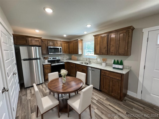 kitchen with stainless steel appliances, dark brown cabinets, wood-type flooring, and sink