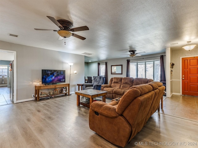 living room featuring ceiling fan, a textured ceiling, and light wood-type flooring