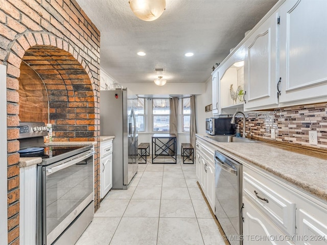 kitchen featuring white cabinets, decorative backsplash, sink, and appliances with stainless steel finishes