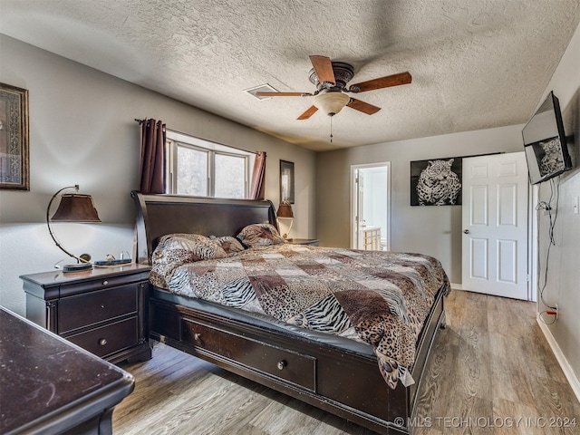 bedroom with ceiling fan, ensuite bathroom, light hardwood / wood-style floors, and a textured ceiling