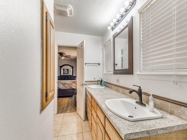 bathroom with tile patterned floors, ceiling fan, vanity, and a textured ceiling