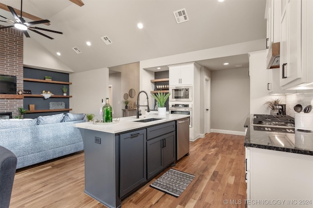 kitchen featuring white cabinetry, sink, dark stone counters, gray cabinets, and a center island with sink