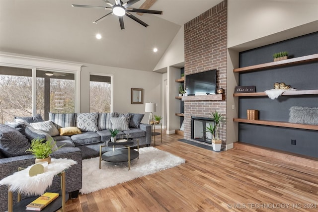 living room with high vaulted ceiling, hardwood / wood-style flooring, a brick fireplace, and ceiling fan