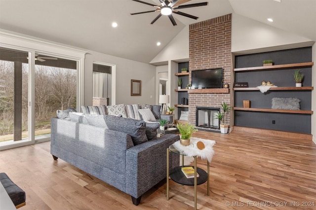 living room featuring light wood-type flooring, a fireplace, and high vaulted ceiling