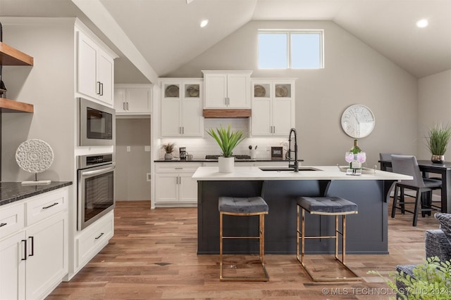 kitchen featuring an island with sink, sink, oven, and light hardwood / wood-style floors