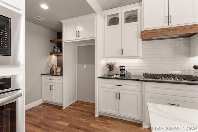 kitchen with hardwood / wood-style floors, backsplash, white cabinetry, and appliances with stainless steel finishes