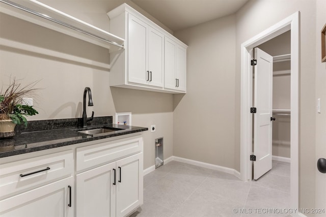 laundry room featuring electric dryer hookup, cabinets, sink, washer hookup, and light tile patterned floors