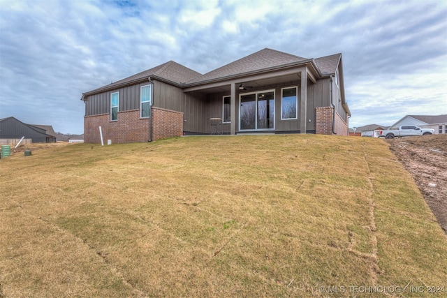 back of property with ceiling fan and a yard