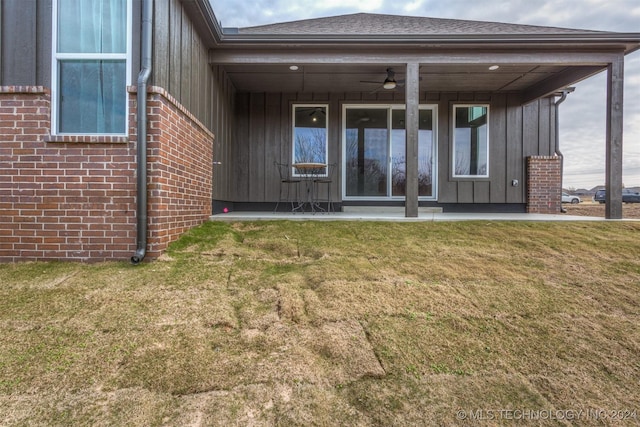 back of property with ceiling fan and a lawn