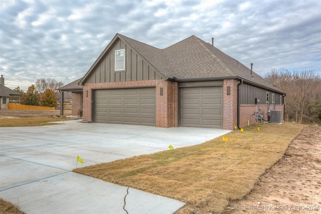 view of property exterior featuring central AC unit, a garage, and a lawn