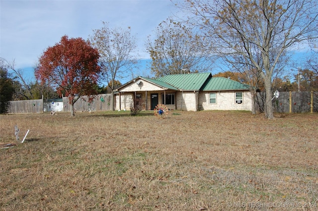 ranch-style house with fence, stone siding, metal roof, and a standing seam roof