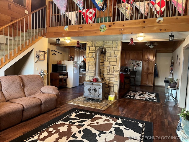 living room with dark wood-type flooring, a high ceiling, a wood stove, and stairs