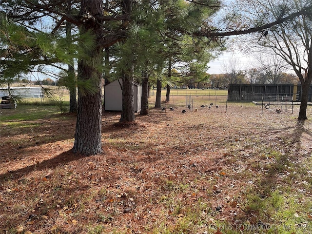 view of yard with a shed, fence, and an outbuilding
