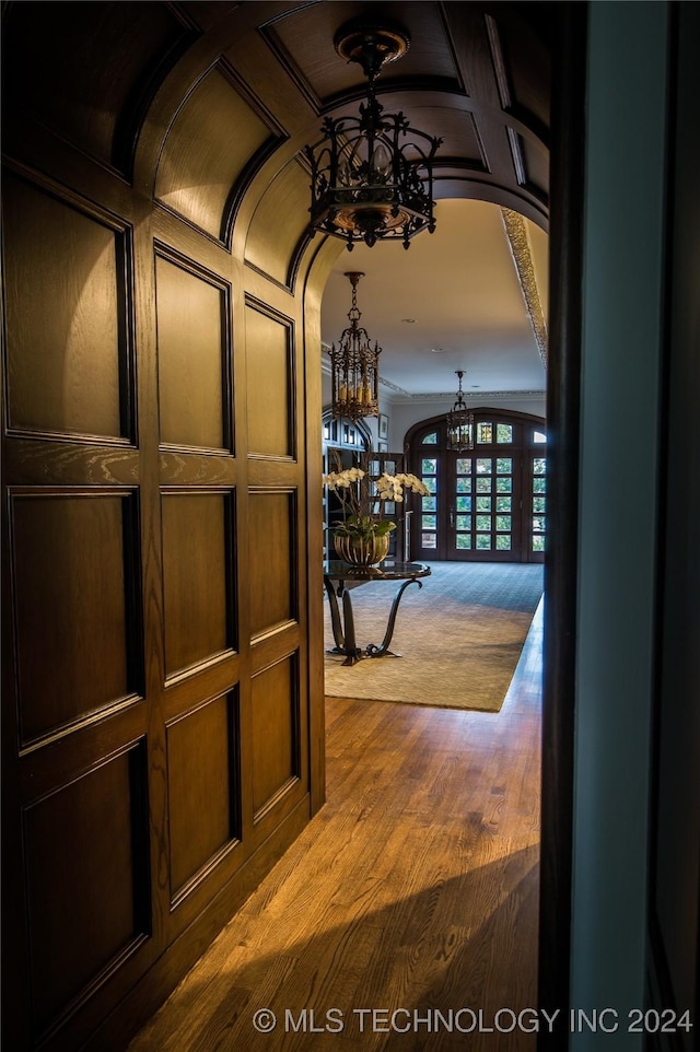 hallway featuring french doors, hardwood / wood-style flooring, an inviting chandelier, and coffered ceiling