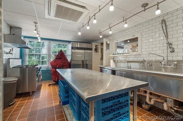 kitchen featuring stainless steel counters, stainless steel appliances, backsplash, tile walls, and dark tile patterned flooring