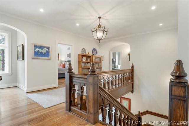 corridor with light wood-type flooring and crown molding