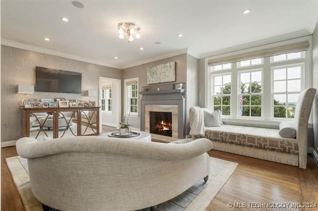 living room featuring ornamental molding, a fireplace, a healthy amount of sunlight, and wood-type flooring