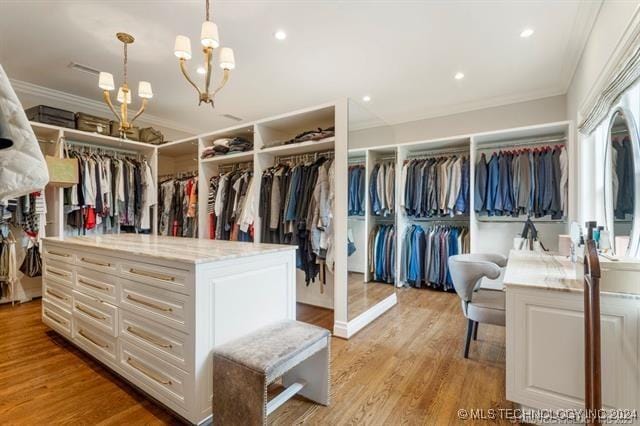 walk in closet with a notable chandelier and light hardwood / wood-style floors