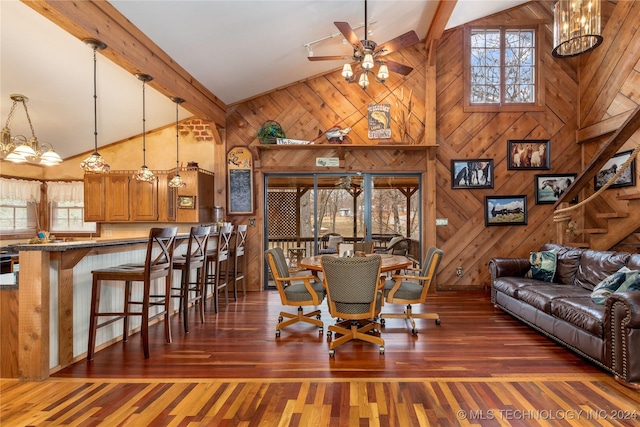 dining area featuring wooden walls, a healthy amount of sunlight, dark wood-type flooring, and high vaulted ceiling