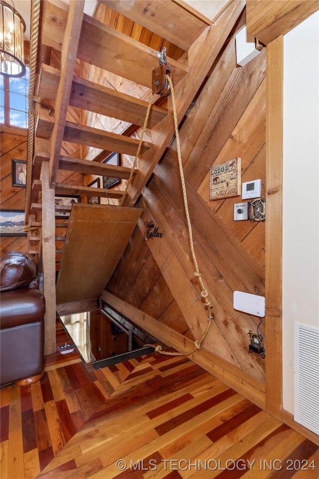 interior space with wooden walls, wood-type flooring, lofted ceiling with beams, wooden ceiling, and a notable chandelier