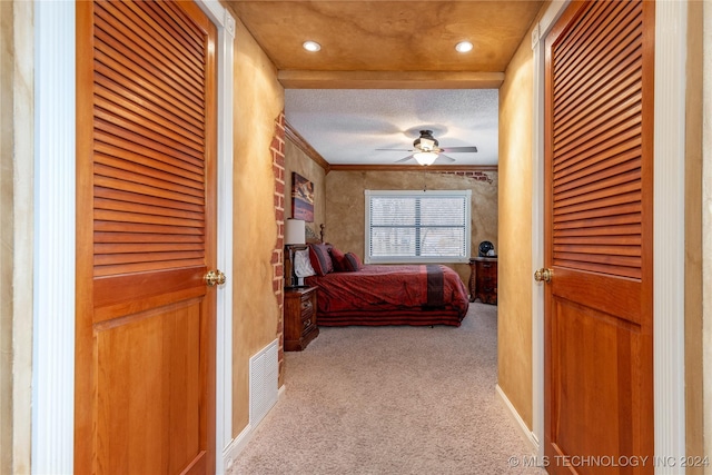 bedroom featuring a textured ceiling, light colored carpet, ceiling fan, and ornamental molding