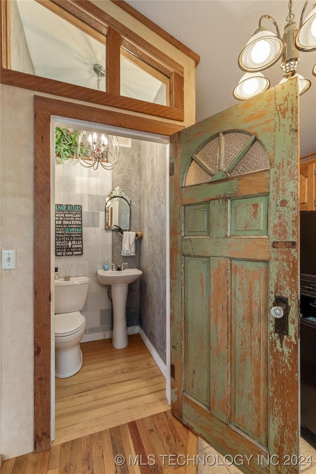 bathroom featuring a chandelier, hardwood / wood-style floors, toilet, and sink