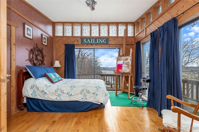 bedroom with wood walls and light hardwood / wood-style floors