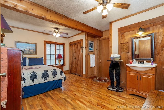 bedroom featuring ceiling fan, sink, light wood-type flooring, and a textured ceiling