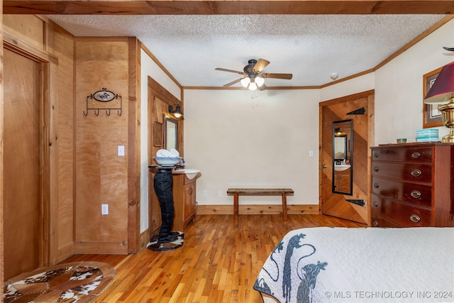 bedroom featuring a textured ceiling, light hardwood / wood-style flooring, ceiling fan, and ornamental molding