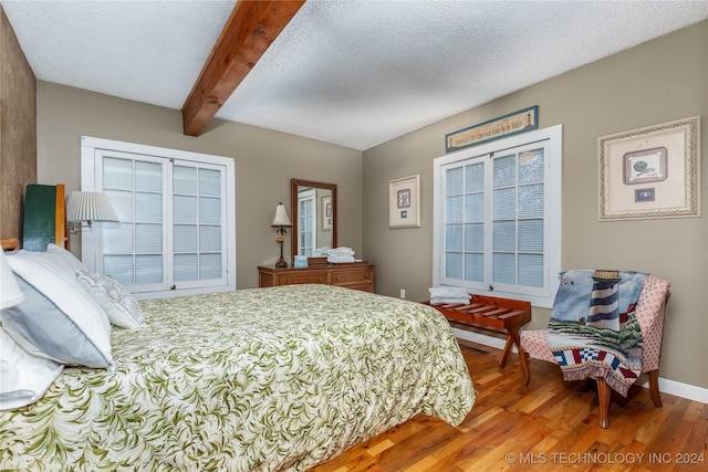 bedroom with wood-type flooring, a textured ceiling, and beam ceiling