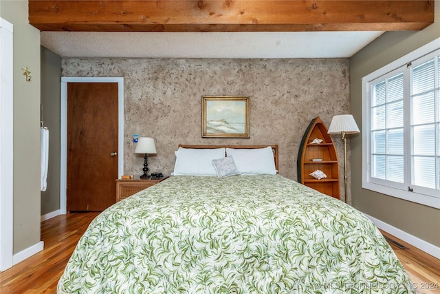 bedroom featuring beam ceiling and hardwood / wood-style flooring