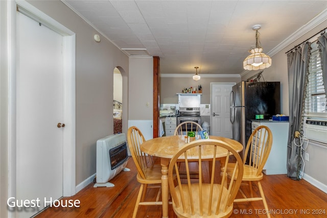 dining area with heating unit, hardwood / wood-style flooring, and crown molding