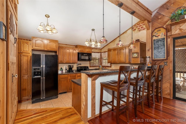 kitchen featuring a breakfast bar, black appliances, a notable chandelier, and light wood-type flooring