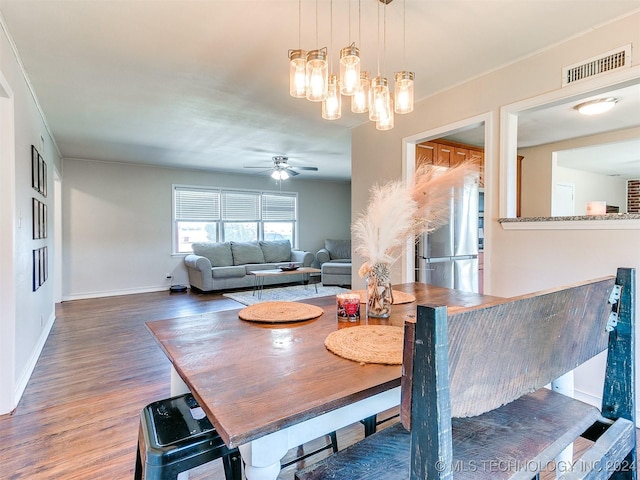 dining area featuring ceiling fan with notable chandelier and dark hardwood / wood-style flooring