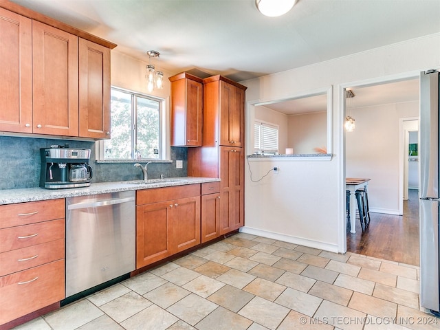 kitchen featuring sink, tasteful backsplash, light stone counters, light hardwood / wood-style flooring, and appliances with stainless steel finishes