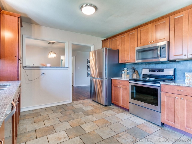 kitchen featuring decorative backsplash, appliances with stainless steel finishes, decorative light fixtures, and light stone counters