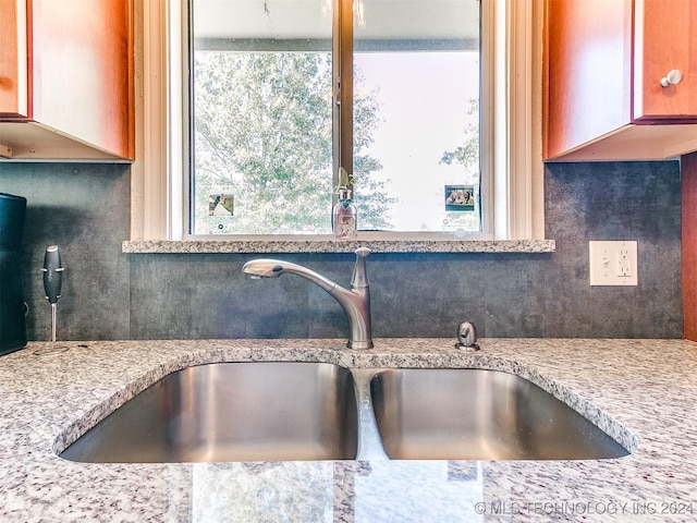 kitchen with decorative backsplash, sink, and light stone counters