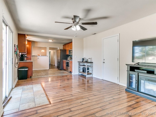 unfurnished living room with light wood-type flooring and ceiling fan