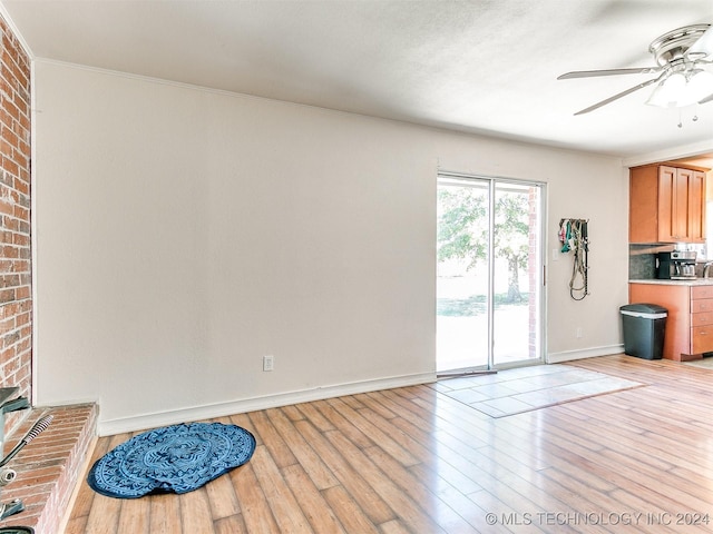 interior space featuring crown molding, light hardwood / wood-style flooring, ceiling fan, and brick wall