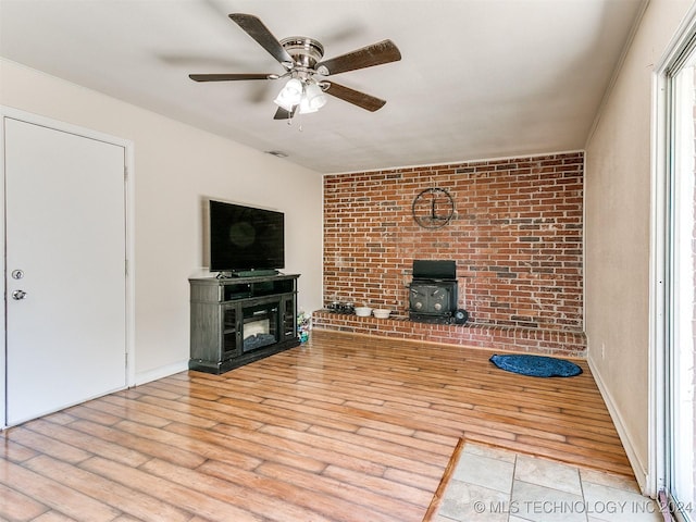 unfurnished living room with ceiling fan, light wood-type flooring, and a wood stove