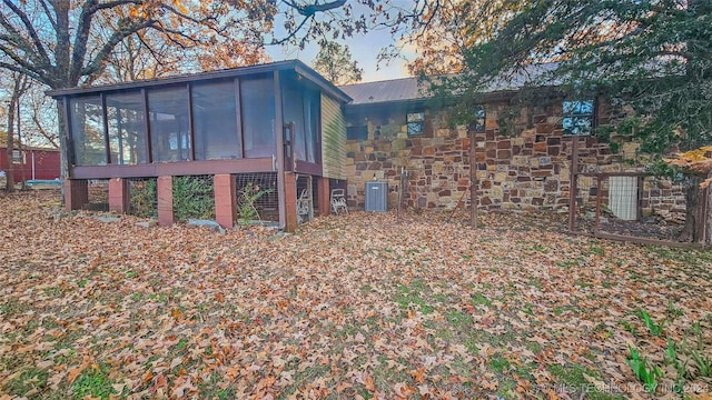 back of property with central AC unit and a sunroom