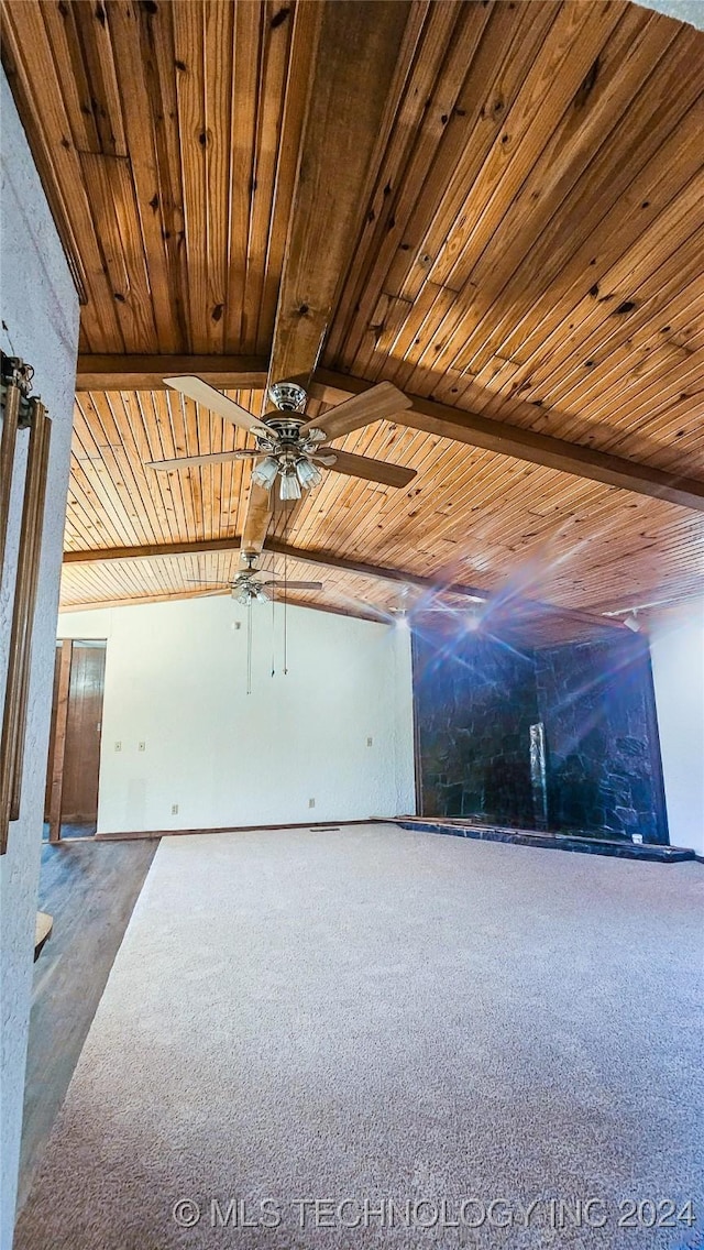 carpeted spare room featuring beamed ceiling, wooden ceiling, and ceiling fan