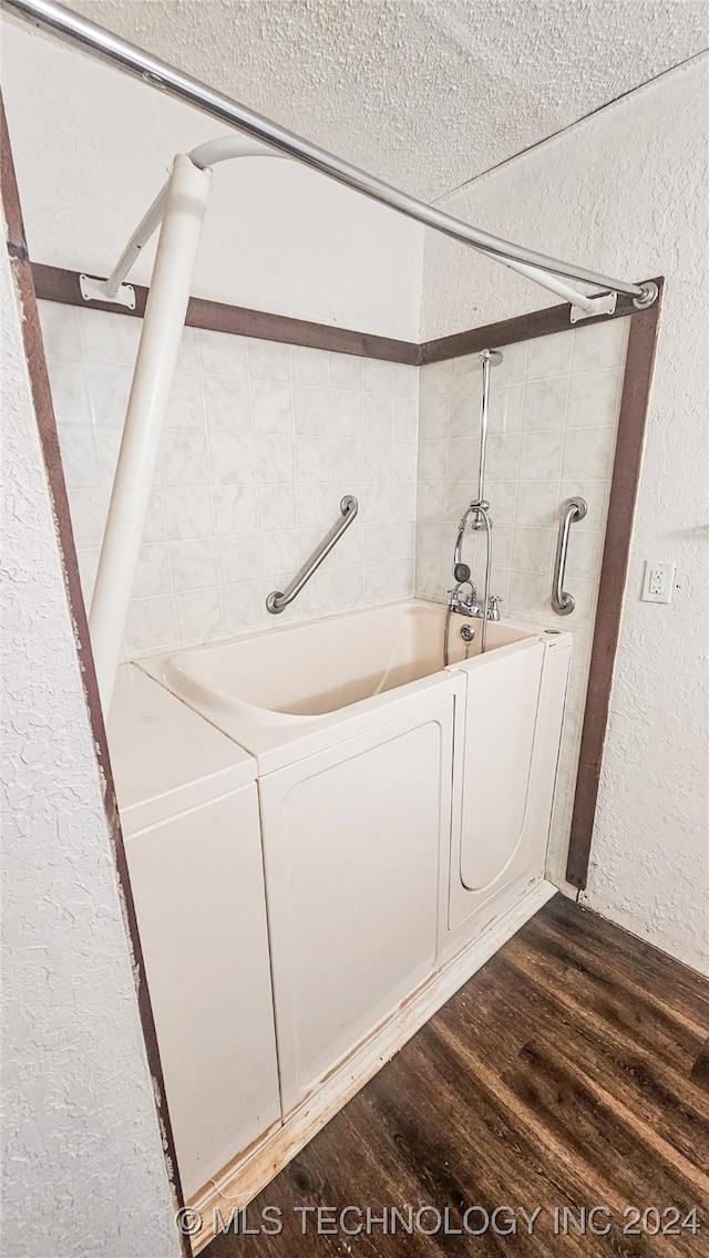 bathroom featuring wood-type flooring, washer and clothes dryer, and bathing tub / shower combination